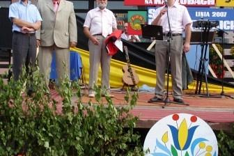 Grupa mężczyzn przemawiająca na festynie sportowym na Kaszubach, widoczne logo.