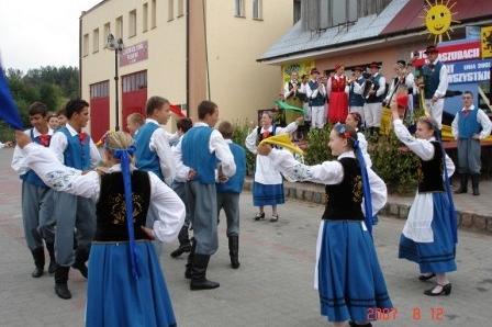 Kaszubi w tradycyjnych strojach tańczą podczas festynu na zewnątrz.