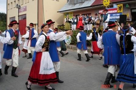 Ludzie w tradycyjnych strojach kaszubskich tańczą na festynie.