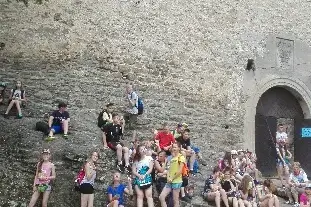 Młodzież siedzi przed jasną skałą