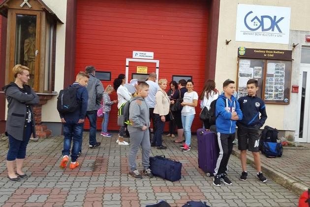 Uczestnicy językowej kolonii w Karpaczu z bagażami stoją przed budynkiem.