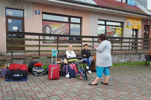 Zbiórka uczestników kolonii językowej z bagażami przed budynkiem.