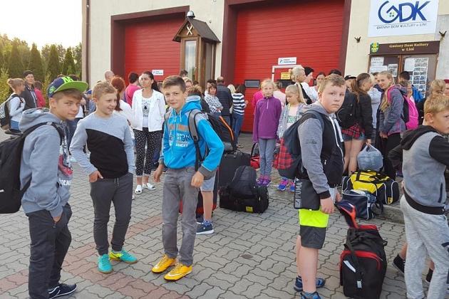 Młodzież z plecakami przed budynkiem, gotowa na przygodę językowej kolonii w Karpaczu.