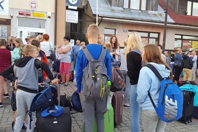 Uczestnicy kolonii językowej z plecakami i walizkami gotowi na przygodę.
