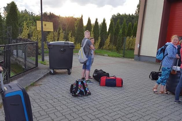 Grupa młodych ludzi z bagażami na zewnątrz budynku kolonii w Karpaczu.