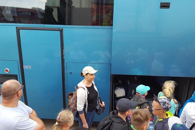Ludzie na kolonii językowej w Karpaczu obok dużego, niebieskiego autokaru.
