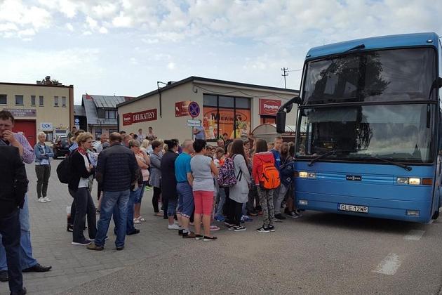 Uczestnicy kolonii w Karpaczu zbierają się przy niebieskim autokarze przed odjazdem.