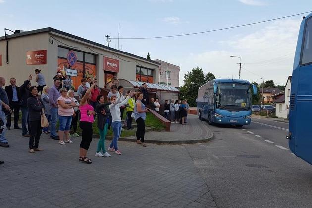 Uczestnicy kolonii letniej zebrani przy autokarach przed budynkiem.