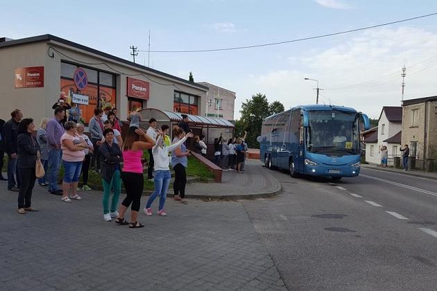 Uczestnicy kolonii językowej z plecakami obok niebieskiego autobusu przed wyjazdem.