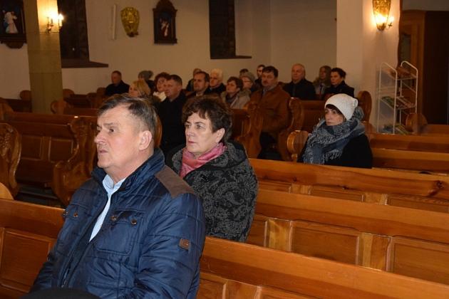 Pszczelarze uczestniczą w świątecznym spotkaniu w kościelnych ławkach.