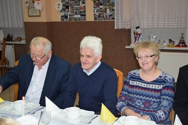 Trzy osoby, dwóch mężczyzn i kobieta, siedzą przy stole podczas spotkania pszczelarzy.