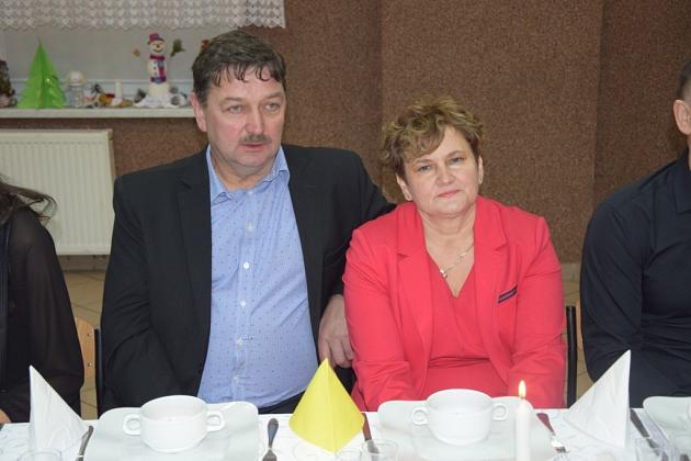 Mężczyzna w marynarce i kobieta w czerwieni na świątecznym spotkaniu pszczelarzy.