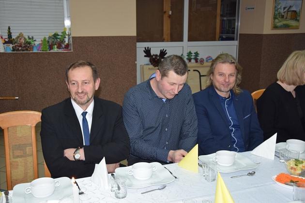 Trzech panów na świątecznym spotkaniu pszczelarzy siedzi przy stole.