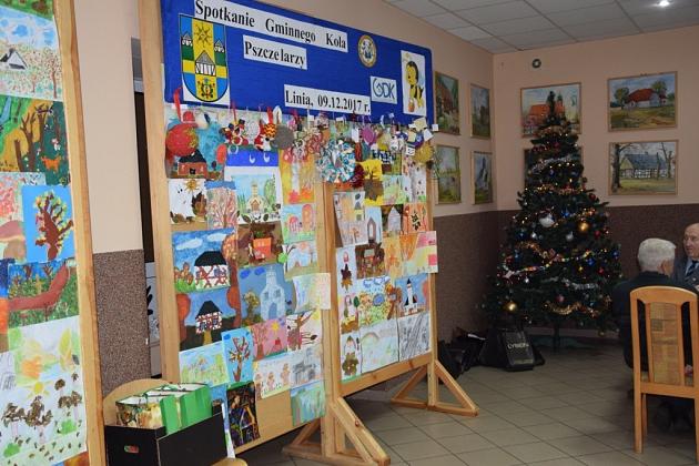 Sala ze sztalugami, dziecięcymi rysunkami i choinką na spotkaniu Koła Pszczelarzy.