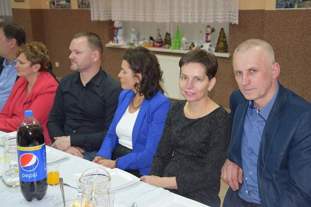Uczestnicy świątecznego spotkania pszczelarzy siedzą przy stole.