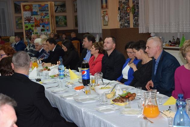 Uczestnicy świątecznego spotkania Gminnego Koła Pszczelarzy siedzą przy stole.