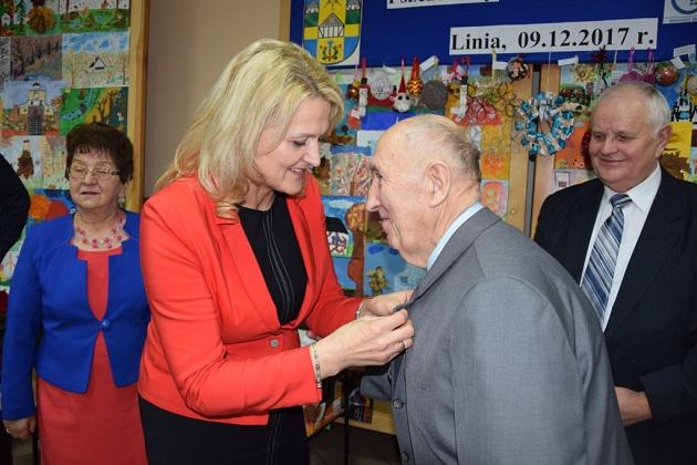 Kobieta wręcza odznaczenie członkowi Koła Pszczelarzy na spotkaniu świątecznym.