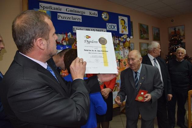 Pszczelarz prezentuje certyfikat na świątecznym spotkaniu Gminnego Koła Pszczelarzy.