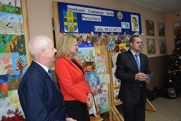Mężczyzna w garniturze przemawia do uczestników świątecznego spotkania pszczelarzy.
