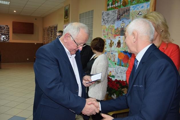 Dwóch panów w garniturach ściska dłonie na spotkaniu pszczelarzy.