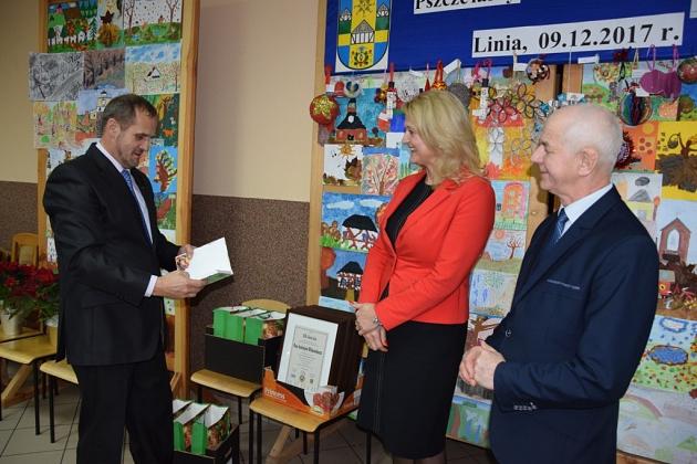 Mężczyzna wręcza dokumenty podczas uroczystego spotkania koła pszczelarzy.