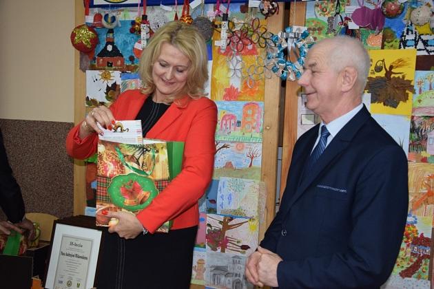 Uśmiechnięta kobieta z prezentem i mężczyzna na świątecznym spotkaniu pszczelarzy.