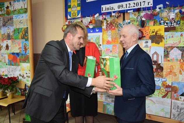 Dwaj mężczyźni wymieniają prezent i uścisk dłoni na świątecznym spotkaniu pszczelarzy.