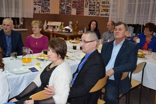 Uczestnicy świątecznego spotkania Gminnego Koła Pszczelarzy siedzą przy stołach.