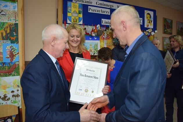 Wręczenie dyplomu członkowi koła pszczelarzy na świątecznym spotkaniu.