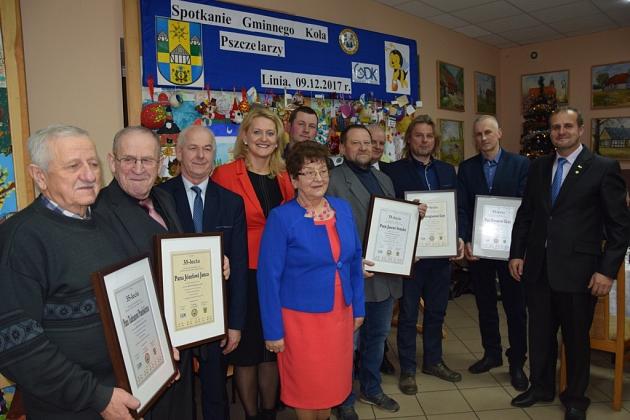 Grupa pszczelarzy odbiera dyplomy na świątecznym spotkaniu w grudniu 2017.